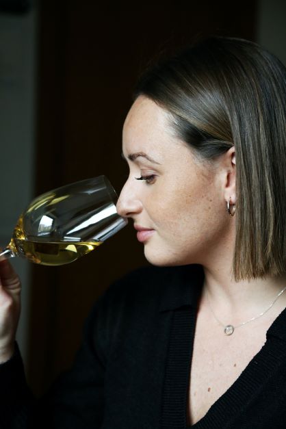 2022-ųjų metų rugsėjo mėnesį tradiciškai vyko Lietuvos someljė čempionatas, kurio nugalėtoja pirmą kartą tapo moteris someljė – Kamilė Bartusevičiūtė (vyno baras „Somm“). Nors pergalė jau jos rankose, Kamilė nustoti nesiruošia ir čempionatą mato kaip bendruomenės šventę, o ne tik varžybas, kuriose laimėjus dalyvauti būtų nebeįdomu. Supažindiname su Kamile¬¬ artimiau.  Studijavo politikos mokslus  Iš Kauno Kamilė atsikraustė į Vilnių tam, kad Vilniaus universitete studijuotų tarptautinių santykių ir politikos mokslus.  Kaip daugelis studentų, dar pirmame kurse mergina įsidarbino restorane. Skirtumas tas, kad Kamilei ši studentiška darbinė patirtis greičiausiai pakeitė visą gyvenimą.  „Skonis mane domino visada. Maistas, vynas, vynas ir maistas... Tad atėjimas dirbti į restoraną greičiausiai sukūrė tą terpę, kur galėjo pilnai atsiskleisti jau manyje iš anksčiau buvusi aistra. Man dirbant buvo nuoširdžiai įdomu.“ Tam tikru metu Kamilė nusprendė pasiimti akademines atostogas ir pailsėti nuo mokslų. Paskatinta draugų ir įkvėpta tuometinio kolegos iš restorano Trinity, būtent tuomet jėgas mergina nutarė išbandyti vyno pasaulyje. Prasidėjo jos darbas specializuotame vyno bare „Somm“.   Apie vyną išmokstama mokantis  Pradėjusi dirbti vyno bare Kamilė greitai suprato, jog žinios apie šimtus skirtingų vynų, kuriuos turi žinoti dirbdamas tokiame restorane, pačios neateis. Reikia mokytis aktyviai ir gana akademiškai.  Pradžioje apie vyną Kamilė mokėsi pati, jai padėdavo ir kolegos, o vėliau kalendoriuje atsirado ir Someljė mokyklos kursai, kurioje Kamilė baigė visus tris Someljė PRO kurso trimestrus, o kitąmet planuoja išsilaikyti ir WSET Level 3 egzaminą ir įgyti tarptautiniu mastu pripažįstamą kvalifikaciją.  Nuolatinis noras mokytis Kamilei kyla ne tik iš natūralaus žingeidumo, bet ir iš to, kad ji, kaip pati sako, nemoka suktis iš situacijos klientui pasakodama išgalvotas istorijas (šypsosi). „Tai tiesiog ne aš. Jei klientas kažko klausia, atsakymą turiu žinoti. Pilstydama iš tuščio į kiaurą neišsisuksiu.”   Galiausiai, nuolat dirbdama su tokiais čempionais kaip Arminas Darasevičius, Lietuvos someljė asociacijos prezidentas, ir Narimantas Miežys, daugkartinis someljė čempionatų nugalėtojas, Kamilė nuo pačios pradžios buvo sužavėta jų žiniomis ir užmotyvuota žinoti dar daugiau, pasirodyti dar geriau. Taip išugdomi čempionai.  Be oficialių studijų ir darbo restorane, mergina neslėpė, jog mokosi ir savarankiškai. „Kartais mokausi žemėlapius. Pavargus nuo jų, sprendžiu testus. Kai atsibosta šie – paskaitau kokį straipsnį ar žiūriu video… Savęs per daug nespaudžiu, kad neperdegčiau, bet mokausi nuolatos,” – komentavo Kamilė.   Kaip pasiruošti čempionatui ir… jį laimėti?  Apie dalyvavimą someljė čempionatuose daugkartinis jo čempionas Narimantas Miežys su Kamile pradėjo kalbėtis vos tik jai pradėjus dirbti vyno bare Somm.   „Viena vertus čempionate tam tikra prasme dalyvauju kas kartą aptarnaudama klientą prie stalo. Tad pasiruošimas tikrajam čempionatui tikrai vyksta kiekvieną dieną.” Kita vertus – to nepakanka.  Ieškodama daugiau informacijos apie čempionatą Kamilė dar savo karjeros pradžioje atrado pasaulio someljė čempionato vaizdo įrašą, kuriame ant scenos lipo tokie vardai kaip Raimunds Tomsons (Latvijos ir Europos someljė čempionas) bei Markas Almertas (Vokietijos ir pasaulio čempionas). „Aš įdėmiai stebėjau, kaip jie šneka ir nesupratau, kaip galima vyno taurėje atrasti tiek daug dalykų. Tai mane paskatino ieškoti ir stengtis dar labiau. Juk, jei kažkam išeina, tai gali išeiti ir man,” – apie pirmąsias ambicijas dalyvauti čempionatuose kalbėjo K. Bartusevičiūtė.  2022-aisiais, kuomet Lietuvos someljė čempionatą laimėjo Kamilė, ji jame dalyvavo jau trečią kartą. Bet ties pergale mergina nesustos. Jai šis čempionatas yra daugiau bendruomenės šventė, kurią someljė turėtų švęsti, tiesiog dalyvaudami ir skatindami vienas kitą tobulėti.   „Mūsų someljė bendruomenė bendruomenė nėra didelė, o čempionatas yra bendruomenės šventė. Nesuprantu, kaip galima nešvęsti,“ – kalbėjo ji. 2022-aisiais Kamilė laimėjo atranką ir išvyko į “ASI bootcamp” – Tarptautinės someljė asociacijos stovyklą Azijoje. Ji, anot merginos, buvo vienas įsimintiniausių patyrimų jos karjeroje. Aklos degustacijos ir skirtingos pakaitos kiekvieną dieną, tarptautinė someljė bendruomenė ir užsimezgusios pažintys – tokios patirtys nutinka kartą gyvenime.   Skonio vertinimas atėjo iš šeimos  Kamilė pasakojo, jog tai, kad ją itin žavi skoniai ir juos kuriantys bei atrandantys žmonės – ne naujiena nei jos draugams, nei šeimai. Mat jos šeimoje visuomet buvo vertinami skoniai, maisto gaminimas ir valgymas. Tai niekada nebuvo tik veikla energijai gauti, bet kažkas daugiau – pasimėgavimas, kažko naujo atradimas.  „Man maistas nėra tik kuras. Nesakau, kad kas dieną turime valgyti prabangiai. Net kiaušinienė iš ryto gali būti ypatinga, jei jai skirsime truputėlį daugiau dėmesio. Skonis, maistas, gėrimai, kaip ir muzika gali būti tiek patyrimas, tiek tiesiog fonas,“ – komentavo ji.  Nors tėvams buvo netikėta, jog studijuoti politikos mokslų į Vilnių išvykusi Kamilė nusprendė karjerą tęsti aptarnavimo srityje, abu tėvai ją šiandien palaiko ir skatina daryti tai, kas jai patinka labiausiai ir suteikia daugiausiai džiaugsmo.   Trumpi klausimai Jei visa gyvenimą reikėtų gerti tik vienos vynuogės vyną, kas tai būtų?  Pasirinkčiau vynuogę, kuri turi daug skirtingų išraiškų, kad neatsibostų. Tad, manau, tai būtų Riesling.   Eini į vestuves, kokį gėrimą dovanoji?  Šampano vintažą. Gal magnumą, jei leidžia piniginė ir draugai labai geri ????  Jei būtum ne someljė, kas būtum?  Kartais pagalvoju, nežinau… Žinau, kad politike būti nenorėčiau nors tai studijavau. Bet iš tikro, nė nenoriu įsivaizduoti kažko kito. Man patinka tai, ką darau dabar ir tuo džiaugiuosi.   TOP 3 vietos atsigerti ar pavalgyti Vilniuje?  Somm, Gaspar‘s ir Alchemikas.   Ko palinkėtum pradedantiesiems someljė?  Būti smalsiems ir atrasti sau įdomų būdą mokytis. 