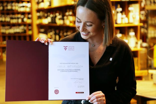 2022-ųjų metų rugsėjo mėnesį tradiciškai vyko Lietuvos someljė čempionatas, kurio nugalėtoja pirmą kartą tapo moteris someljė – Kamilė Bartusevičiūtė (vyno baras „Somm“). Nors pergalė jau jos rankose, Kamilė nustoti nesiruošia ir čempionatą mato kaip bendruomenės šventę, o ne tik varžybas, kuriose laimėjus dalyvauti būtų nebeįdomu. Supažindiname su Kamile¬¬ artimiau.  Studijavo politikos mokslus  Iš Kauno Kamilė atsikraustė į Vilnių tam, kad Vilniaus universitete studijuotų tarptautinių santykių ir politikos mokslus.  Kaip daugelis studentų, dar pirmame kurse mergina įsidarbino restorane. Skirtumas tas, kad Kamilei ši studentiška darbinė patirtis greičiausiai pakeitė visą gyvenimą.  „Skonis mane domino visada. Maistas, vynas, vynas ir maistas... Tad atėjimas dirbti į restoraną greičiausiai sukūrė tą terpę, kur galėjo pilnai atsiskleisti jau manyje iš anksčiau buvusi aistra. Man dirbant buvo nuoširdžiai įdomu.“ Tam tikru metu Kamilė nusprendė pasiimti akademines atostogas ir pailsėti nuo mokslų. Paskatinta draugų ir įkvėpta tuometinio kolegos iš restorano Trinity, būtent tuomet jėgas mergina nutarė išbandyti vyno pasaulyje. Prasidėjo jos darbas specializuotame vyno bare „Somm“.   Apie vyną išmokstama mokantis  Pradėjusi dirbti vyno bare Kamilė greitai suprato, jog žinios apie šimtus skirtingų vynų, kuriuos turi žinoti dirbdamas tokiame restorane, pačios neateis. Reikia mokytis aktyviai ir gana akademiškai.  Pradžioje apie vyną Kamilė mokėsi pati, jai padėdavo ir kolegos, o vėliau kalendoriuje atsirado ir Someljė mokyklos kursai, kurioje Kamilė baigė visus tris Someljė PRO kurso trimestrus, o kitąmet planuoja išsilaikyti ir WSET Level 3 egzaminą ir įgyti tarptautiniu mastu pripažįstamą kvalifikaciją.  Nuolatinis noras mokytis Kamilei kyla ne tik iš natūralaus žingeidumo, bet ir iš to, kad ji, kaip pati sako, nemoka suktis iš situacijos klientui pasakodama išgalvotas istorijas (šypsosi). „Tai tiesiog ne aš. Jei klientas kažko klausia, atsakymą turiu žinoti. Pilstydama iš tuščio į kiaurą neišsisuksiu.”   Galiausiai, nuolat dirbdama su tokiais čempionais kaip Arminas Darasevičius, Lietuvos someljė asociacijos prezidentas, ir Narimantas Miežys, daugkartinis someljė čempionatų nugalėtojas, Kamilė nuo pačios pradžios buvo sužavėta jų žiniomis ir užmotyvuota žinoti dar daugiau, pasirodyti dar geriau. Taip išugdomi čempionai.  Be oficialių studijų ir darbo restorane, mergina neslėpė, jog mokosi ir savarankiškai. „Kartais mokausi žemėlapius. Pavargus nuo jų, sprendžiu testus. Kai atsibosta šie – paskaitau kokį straipsnį ar žiūriu video… Savęs per daug nespaudžiu, kad neperdegčiau, bet mokausi nuolatos,” – komentavo Kamilė.   Kaip pasiruošti čempionatui ir… jį laimėti?  Apie dalyvavimą someljė čempionatuose daugkartinis jo čempionas Narimantas Miežys su Kamile pradėjo kalbėtis vos tik jai pradėjus dirbti vyno bare Somm.   „Viena vertus čempionate tam tikra prasme dalyvauju kas kartą aptarnaudama klientą prie stalo. Tad pasiruošimas tikrajam čempionatui tikrai vyksta kiekvieną dieną.” Kita vertus – to nepakanka.  Ieškodama daugiau informacijos apie čempionatą Kamilė dar savo karjeros pradžioje atrado pasaulio someljė čempionato vaizdo įrašą, kuriame ant scenos lipo tokie vardai kaip Raimunds Tomsons (Latvijos ir Europos someljė čempionas) bei Markas Almertas (Vokietijos ir pasaulio čempionas). „Aš įdėmiai stebėjau, kaip jie šneka ir nesupratau, kaip galima vyno taurėje atrasti tiek daug dalykų. Tai mane paskatino ieškoti ir stengtis dar labiau. Juk, jei kažkam išeina, tai gali išeiti ir man,” – apie pirmąsias ambicijas dalyvauti čempionatuose kalbėjo K. Bartusevičiūtė.  2022-aisiais, kuomet Lietuvos someljė čempionatą laimėjo Kamilė, ji jame dalyvavo jau trečią kartą. Bet ties pergale mergina nesustos. Jai šis čempionatas yra daugiau bendruomenės šventė, kurią someljė turėtų švęsti, tiesiog dalyvaudami ir skatindami vienas kitą tobulėti.   „Mūsų someljė bendruomenė bendruomenė nėra didelė, o čempionatas yra bendruomenės šventė. Nesuprantu, kaip galima nešvęsti,“ – kalbėjo ji. 2022-aisiais Kamilė laimėjo atranką ir išvyko į “ASI bootcamp” – Tarptautinės someljė asociacijos stovyklą Azijoje. Ji, anot merginos, buvo vienas įsimintiniausių patyrimų jos karjeroje. Aklos degustacijos ir skirtingos pakaitos kiekvieną dieną, tarptautinė someljė bendruomenė ir užsimezgusios pažintys – tokios patirtys nutinka kartą gyvenime.   Skonio vertinimas atėjo iš šeimos  Kamilė pasakojo, jog tai, kad ją itin žavi skoniai ir juos kuriantys bei atrandantys žmonės – ne naujiena nei jos draugams, nei šeimai. Mat jos šeimoje visuomet buvo vertinami skoniai, maisto gaminimas ir valgymas. Tai niekada nebuvo tik veikla energijai gauti, bet kažkas daugiau – pasimėgavimas, kažko naujo atradimas.  „Man maistas nėra tik kuras. Nesakau, kad kas dieną turime valgyti prabangiai. Net kiaušinienė iš ryto gali būti ypatinga, jei jai skirsime truputėlį daugiau dėmesio. Skonis, maistas, gėrimai, kaip ir muzika gali būti tiek patyrimas, tiek tiesiog fonas,“ – komentavo ji.  Nors tėvams buvo netikėta, jog studijuoti politikos mokslų į Vilnių išvykusi Kamilė nusprendė karjerą tęsti aptarnavimo srityje, abu tėvai ją šiandien palaiko ir skatina daryti tai, kas jai patinka labiausiai ir suteikia daugiausiai džiaugsmo.   Trumpi klausimai Jei visa gyvenimą reikėtų gerti tik vienos vynuogės vyną, kas tai būtų?  Pasirinkčiau vynuogę, kuri turi daug skirtingų išraiškų, kad neatsibostų. Tad, manau, tai būtų Riesling.   Eini į vestuves, kokį gėrimą dovanoji?  Šampano vintažą. Gal magnumą, jei leidžia piniginė ir draugai labai geri ????  Jei būtum ne someljė, kas būtum?  Kartais pagalvoju, nežinau… Žinau, kad politike būti nenorėčiau nors tai studijavau. Bet iš tikro, nė nenoriu įsivaizduoti kažko kito. Man patinka tai, ką darau dabar ir tuo džiaugiuosi.   TOP 3 vietos atsigerti ar pavalgyti Vilniuje?  Somm, Gaspar‘s ir Alchemikas.   Ko palinkėtum pradedantiesiems someljė?  Būti smalsiems ir atrasti sau įdomų būdą mokytis. 